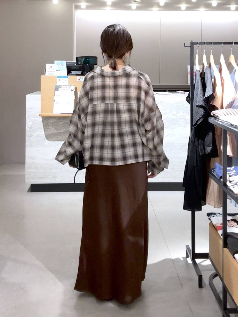 ブラウン系のスカート、ブラック系のパンプス、ブラック系のトートバッグを着用したレディースの春コーディネートの2枚目の写真