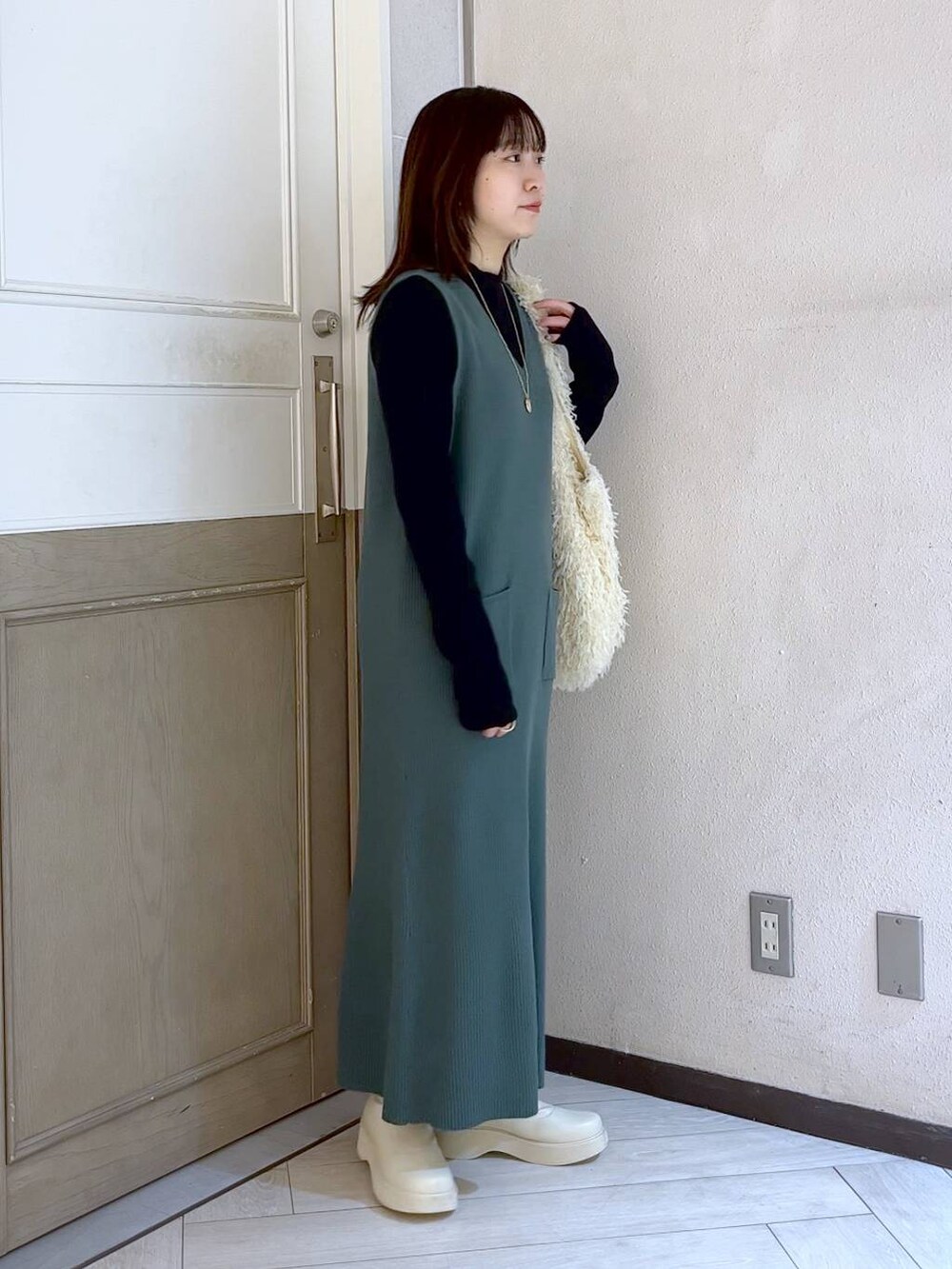 ホワイト系のブーツ、グリーン系のワンピース、ホワイト系のトートバッグを着用したレディースの冬コーディネートの3枚目の写真