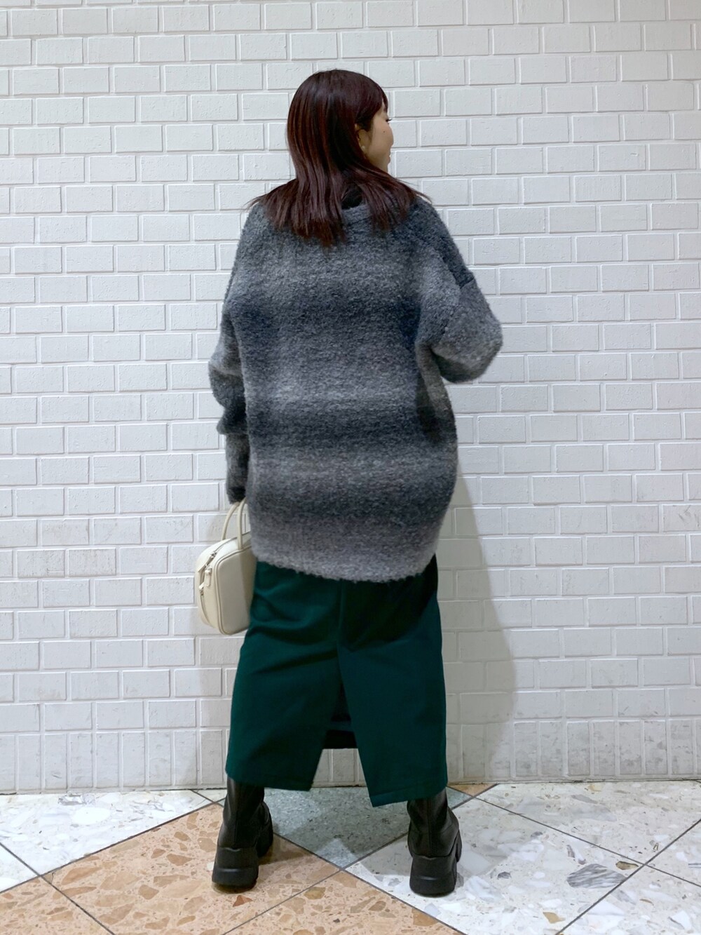 ブラック系のトップス、ブラック系のニット/セーター、グリーン系のスカートを着用したレディースの冬コーディネートの3枚目の写真