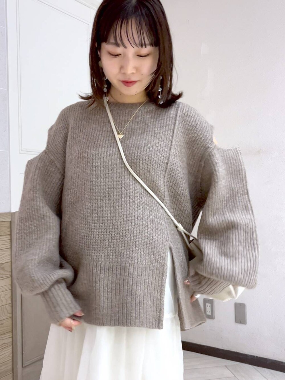 ホワイト系のショルダーバッグ、ブラック系のブーツ、ホワイト系のスカートを着用したレディースの秋コーディネートの7枚目の写真