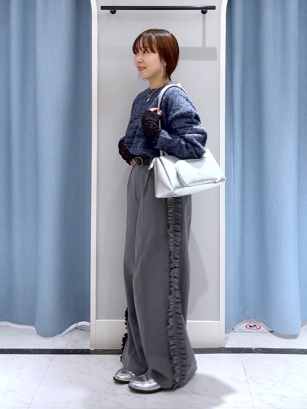 シルバー系のショルダーバッグ、シルバー系のローファー、ブルー系のニット/セーターを着用したレディースの冬コーディネートの3枚目の写真