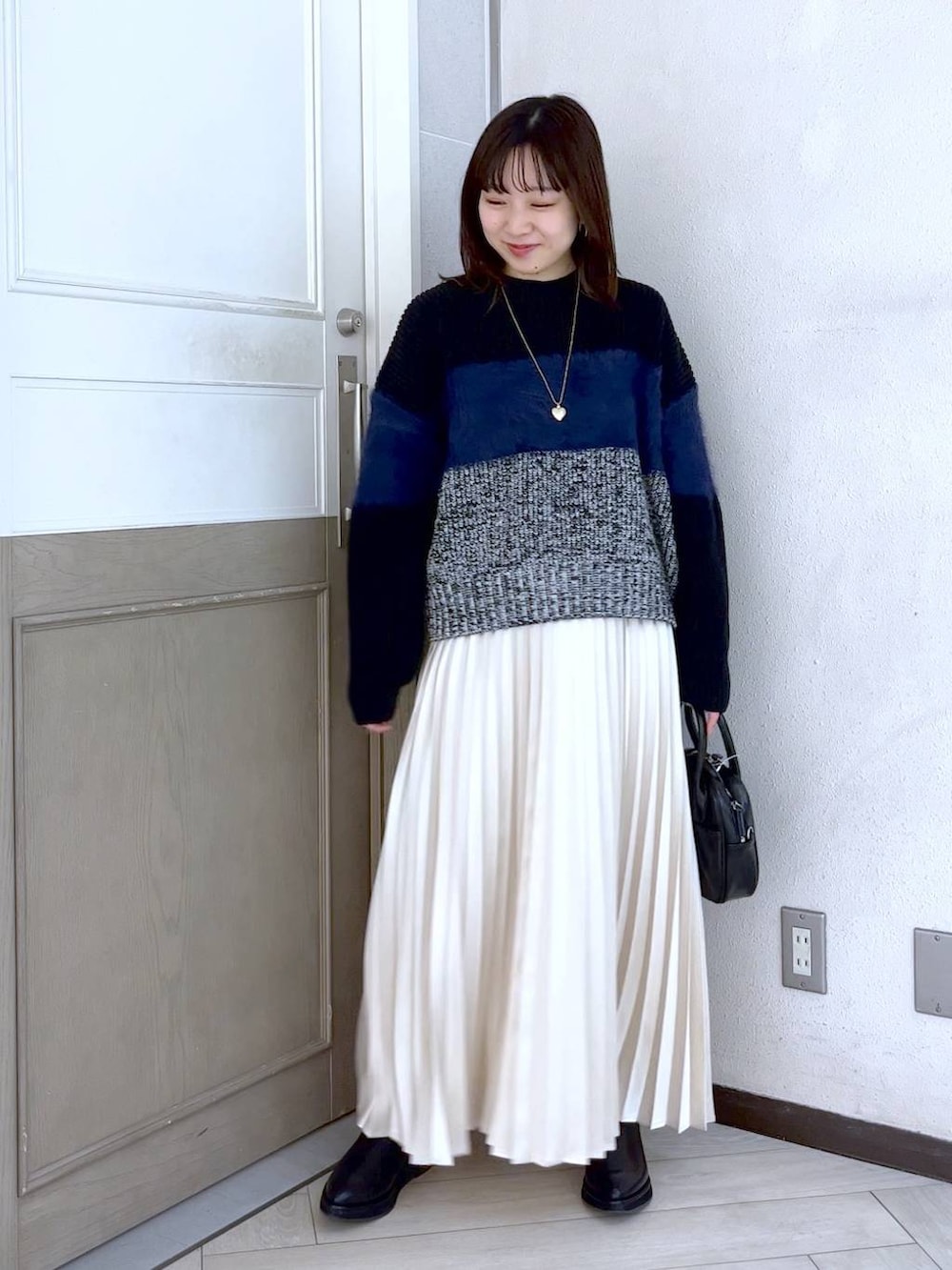 ブラック系のニット/セーター、ブラック系のブーツ、ブラック系のボストンバッグを着用したレディースの冬コーディネートの2枚目の写真