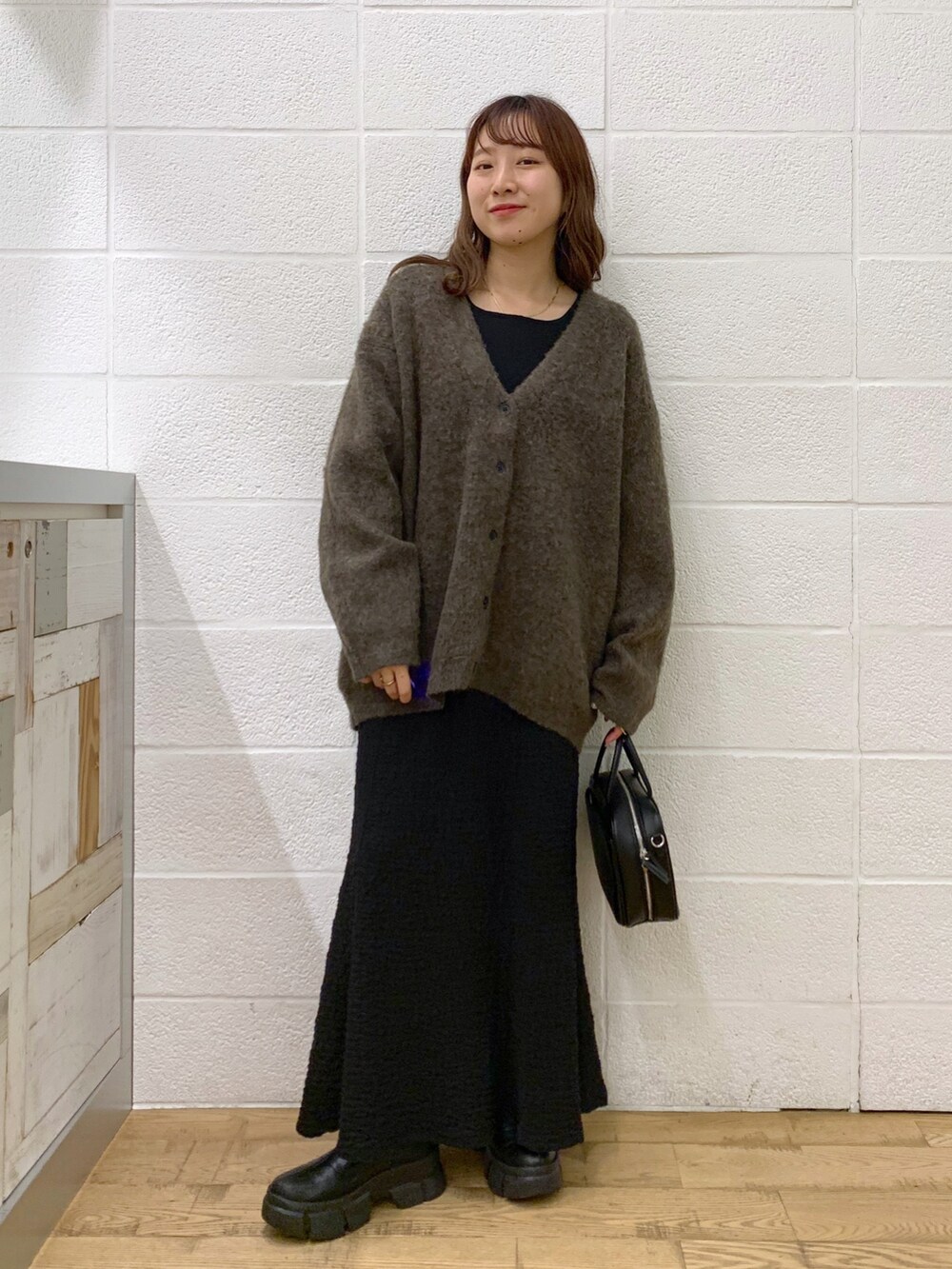 ブラウン系のカーディガン/ボレロ、ブラック系のスカート、ブラック系のバッグを着用したレディースの秋コーディネートの2枚目の写真