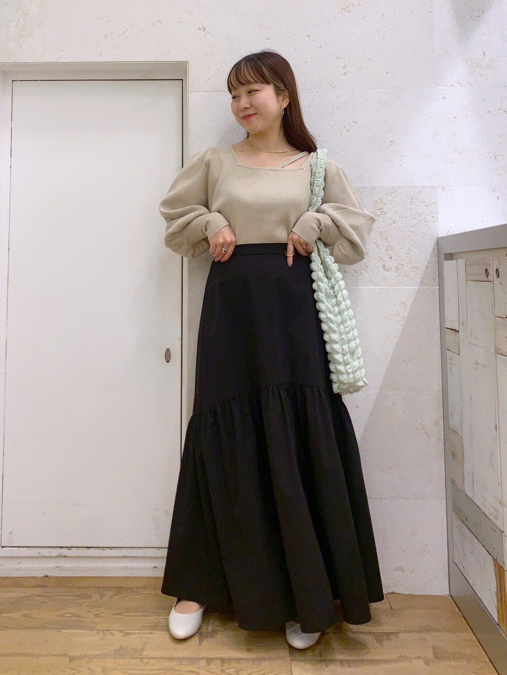 ホワイト系のトップス、ブラック系のスカート、ホワイト系のシューズを着用したレディースの春コーディネートの2枚目の写真