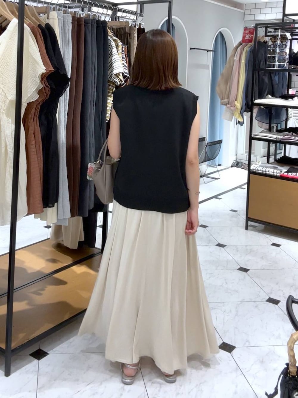 ブラウン系のTシャツ/カットソー、シルバー系のサンダル、ホワイト系のスカートを着用したレディースの夏コーディネートの3枚目の写真