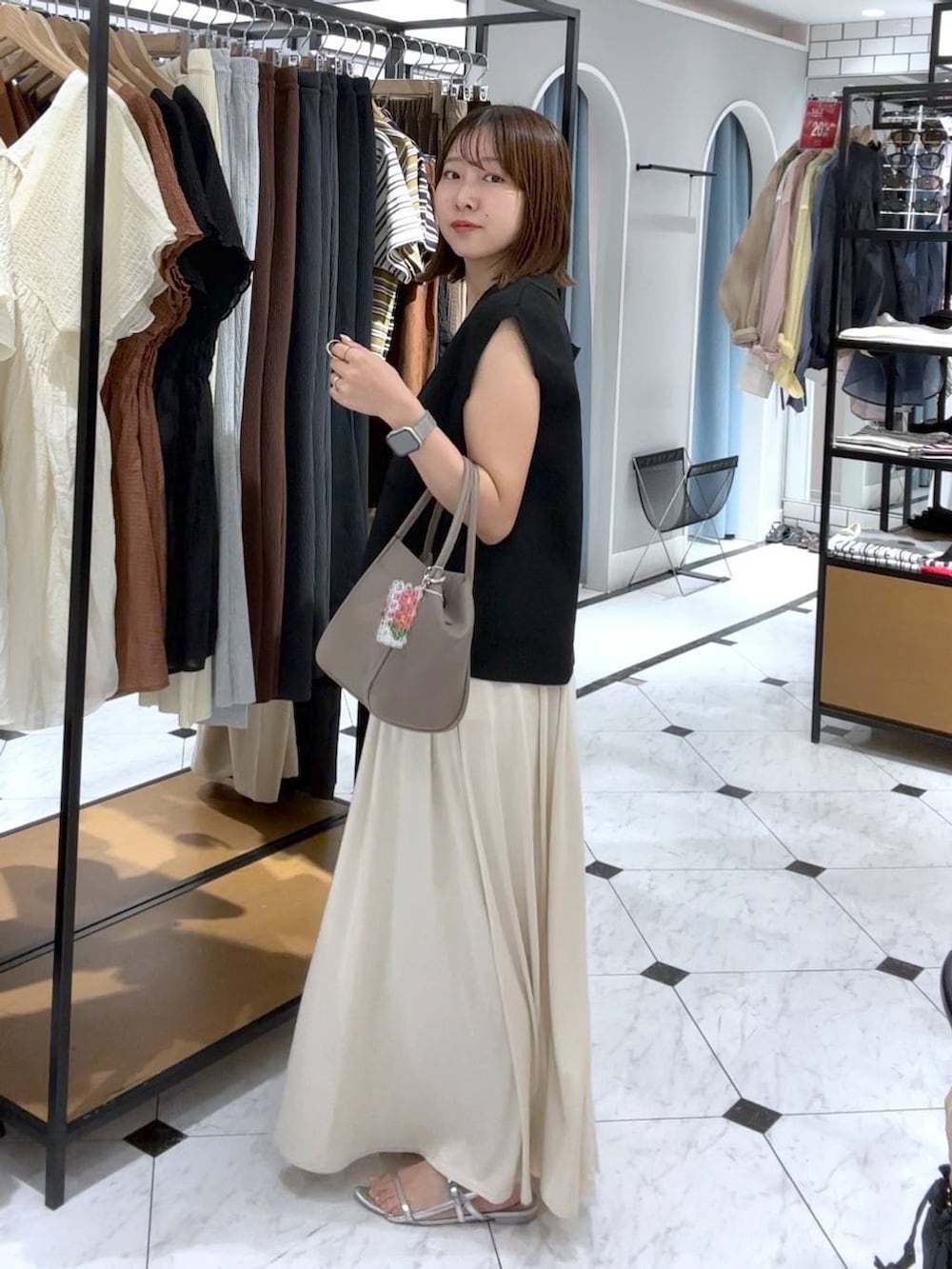 ブラウン系のTシャツ/カットソー、シルバー系のサンダル、ホワイト系のスカートを着用したレディースの夏コーディネートの2枚目の写真