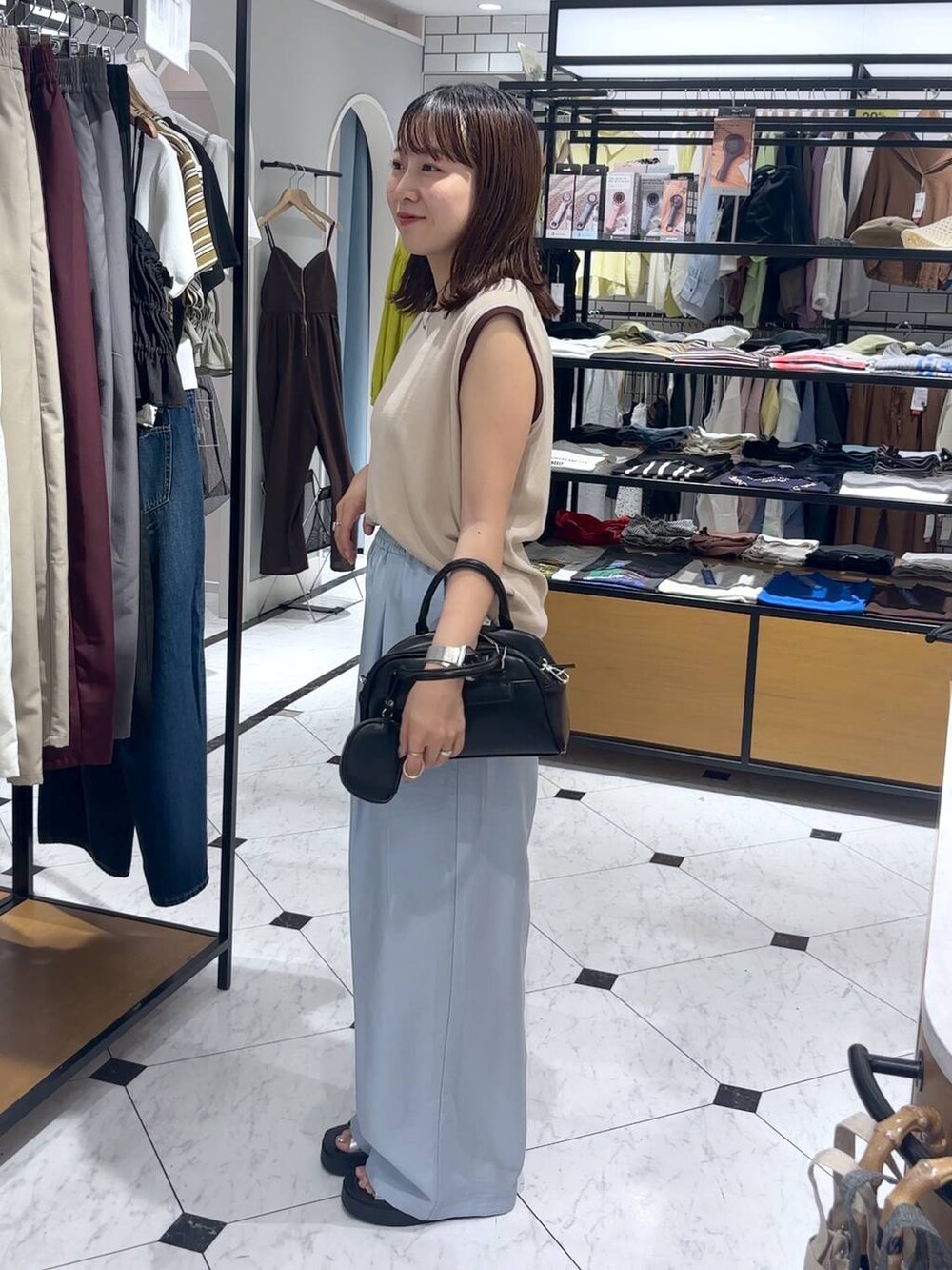 シルバー系のサンダル、ブルー系のその他パンツ、ブラック系のショルダーバッグを着用したレディースの夏コーディネートの2枚目の写真