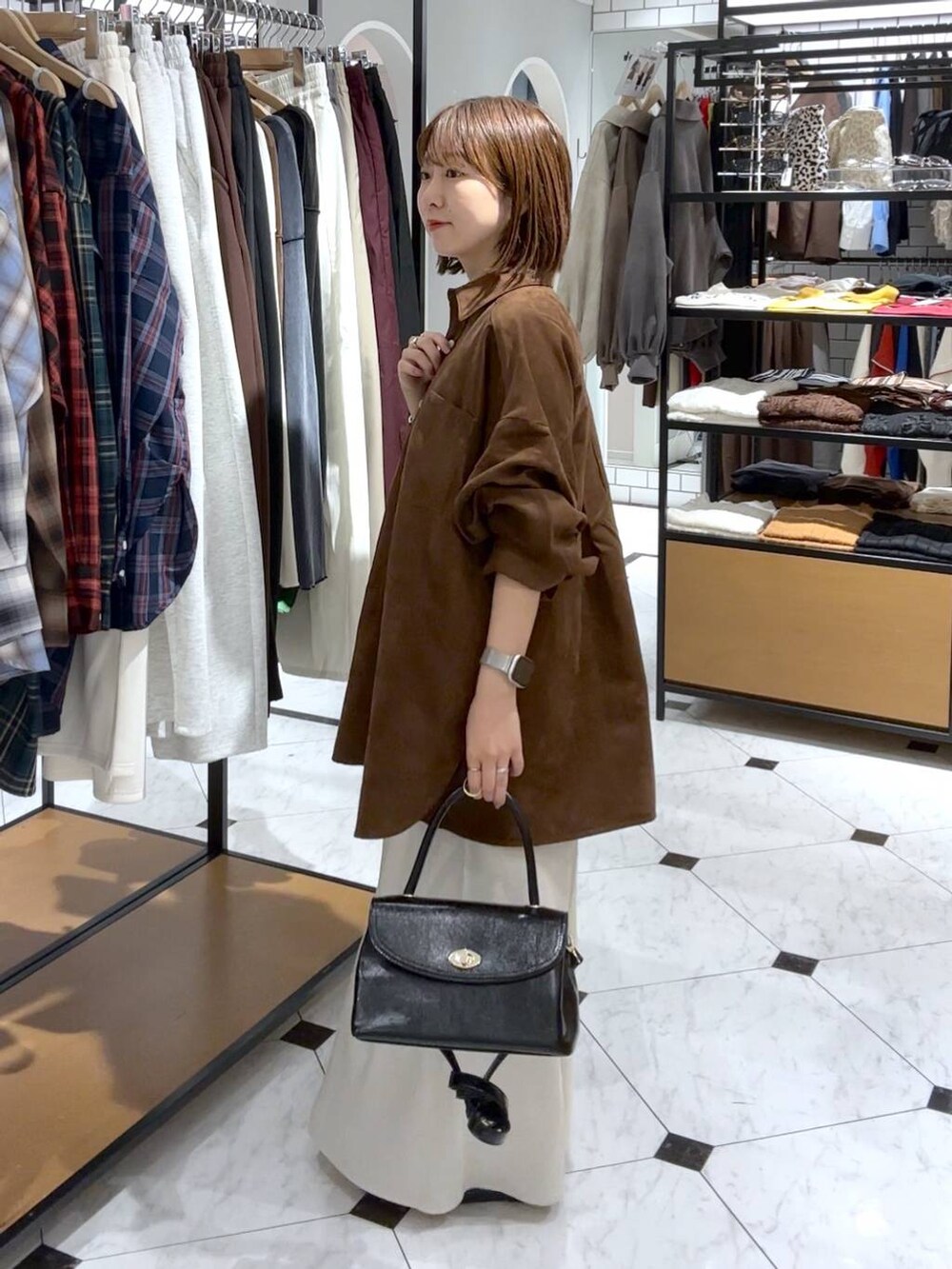 ホワイト系のスカート、ブラック系のボストンバッグ、ブラック系のパンプスを着用したレディースの秋コーディネートの2枚目の写真