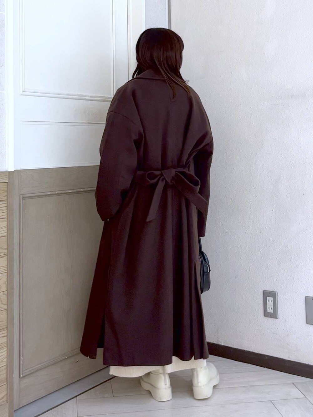 ブラウン系のトレンチコート、ホワイト系のブーツ、ホワイト系のワンピースを着用したレディースの冬コーディネートの2枚目の写真