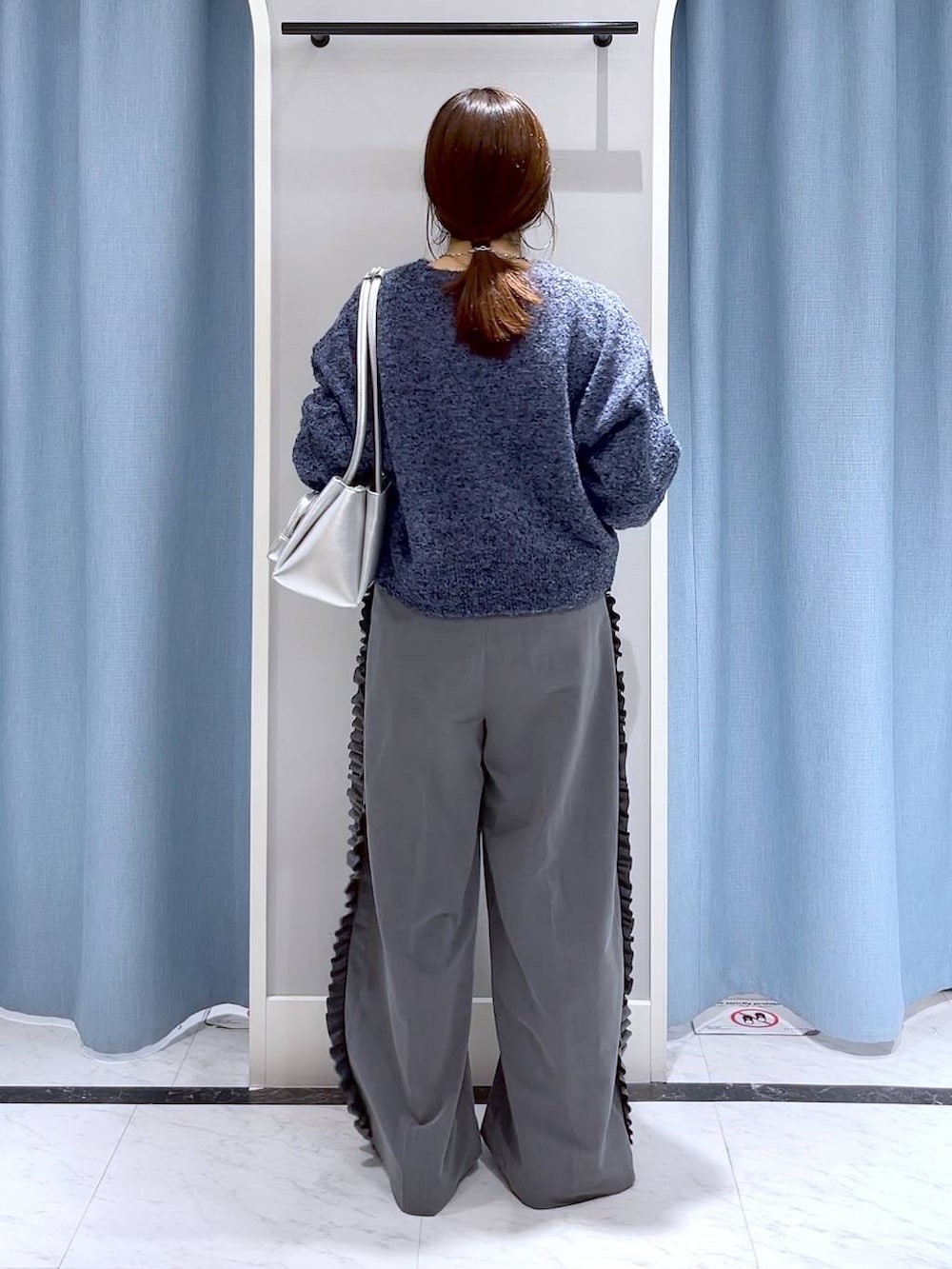 シルバー系のショルダーバッグ、シルバー系のローファー、ブルー系のニット/セーターを着用したレディースの冬コーディネートの4枚目の写真