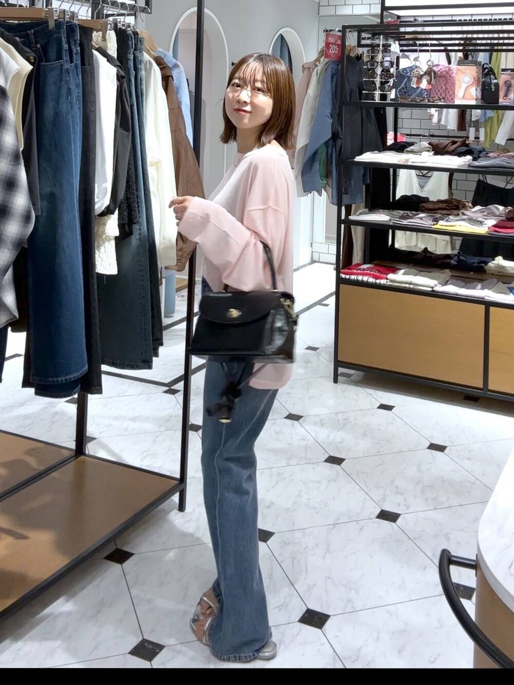 シルバー系のサンダル、ブルー系のデニムパンツ、ブラック系のボストンバッグを着用したレディースの夏コーディネートの2枚目の写真