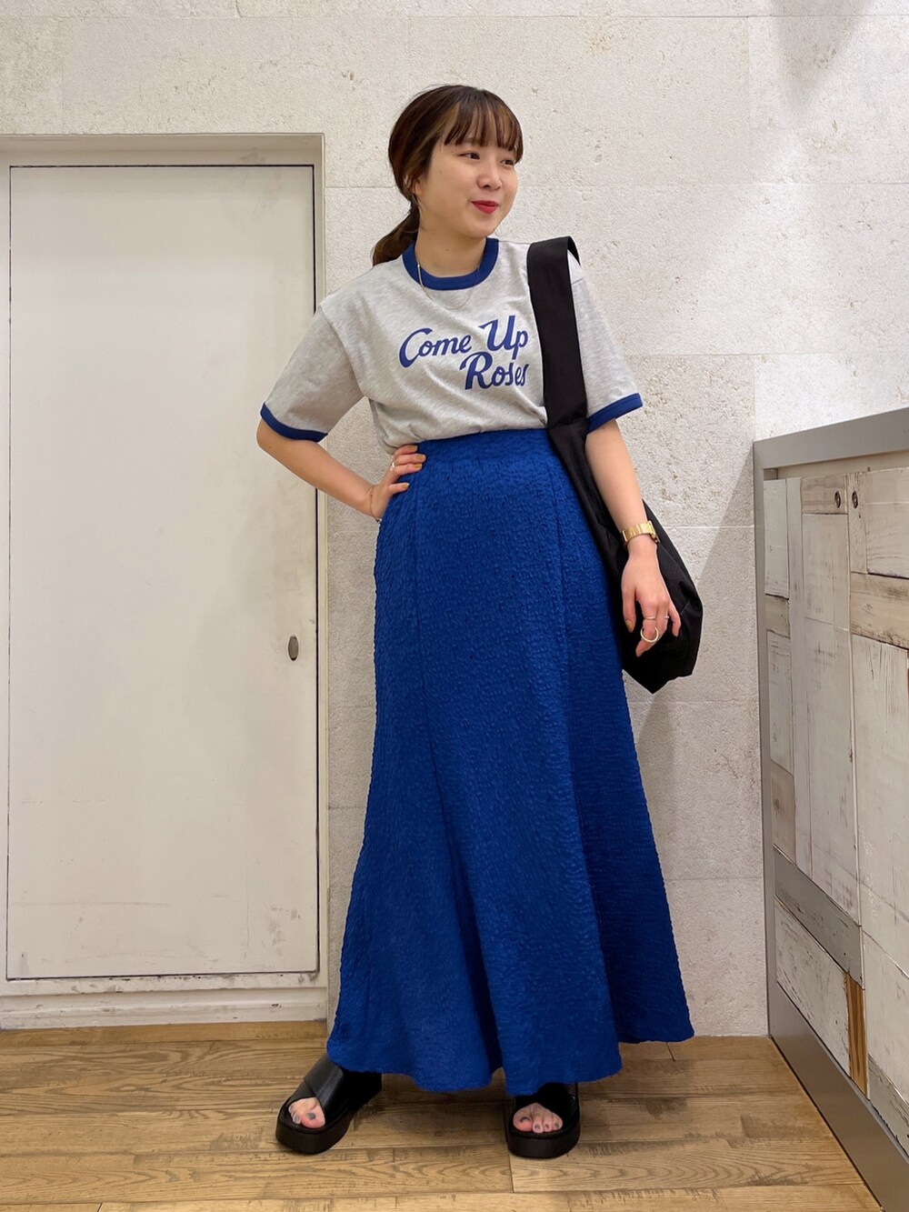 グレー系のTシャツ/カットソー、ブルー系のスカート、ブラック系のシューズを着用したレディースの春コーディネートの2枚目の写真