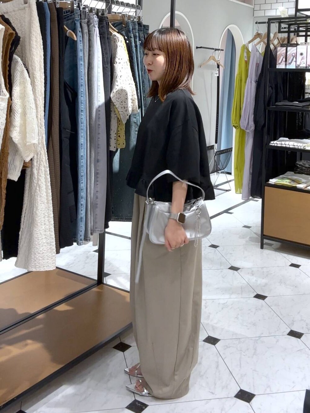 シルバー系のトートバッグ、シルバー系のサンダル、ベージュ系のその他パンツを着用したレディースの夏コーディネートの3枚目の写真