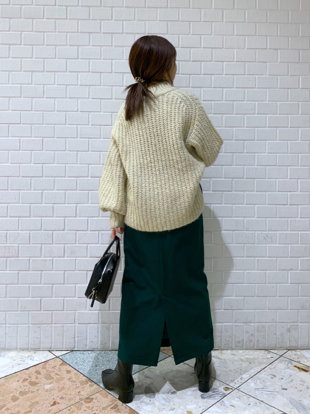 ホワイト系のトップス、グリーン系のスカート、ブラック系のバッグを着用したレディースの冬コーディネートの3枚目の写真