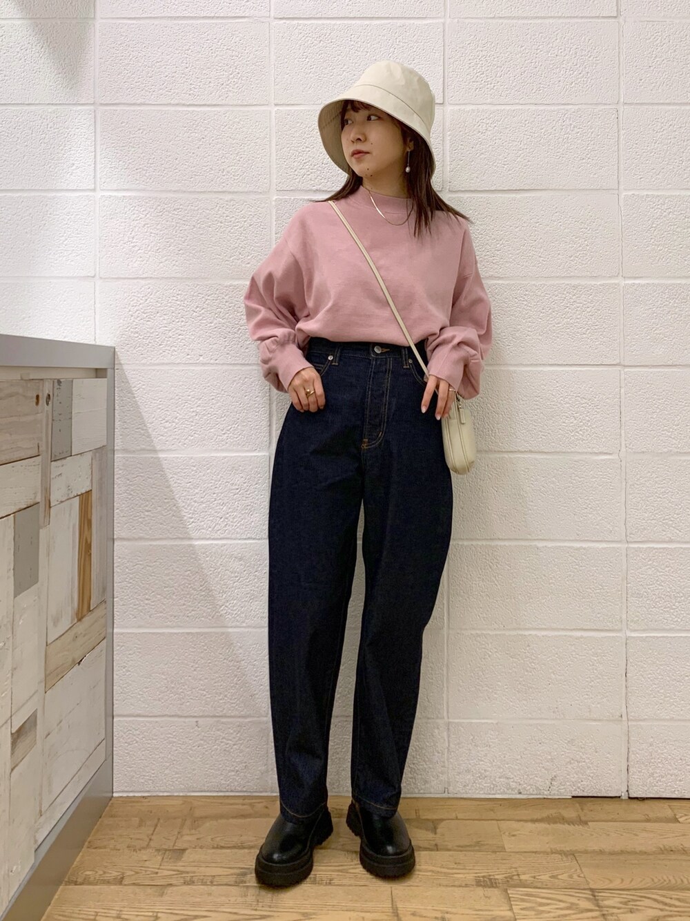 ピンク系のトップス、ブルー系のデニムパンツ、ブラック系のバッグを着用したレディースの秋コーディネートの3枚目の写真