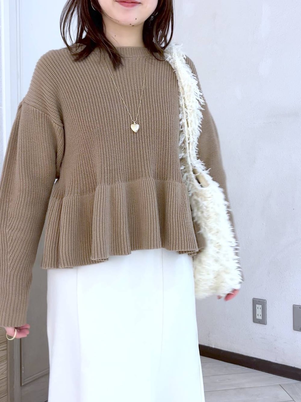 ホワイト系のスカート、ブラウン系のパンプス、ベージュ系のニット/セーターを着用したレディースの冬コーディネートの4枚目の写真