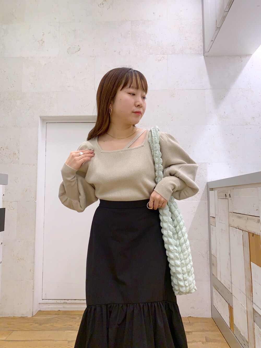 ホワイト系のトップス、ブラック系のスカート、ホワイト系のシューズを着用したレディースの春コーディネートの4枚目の写真