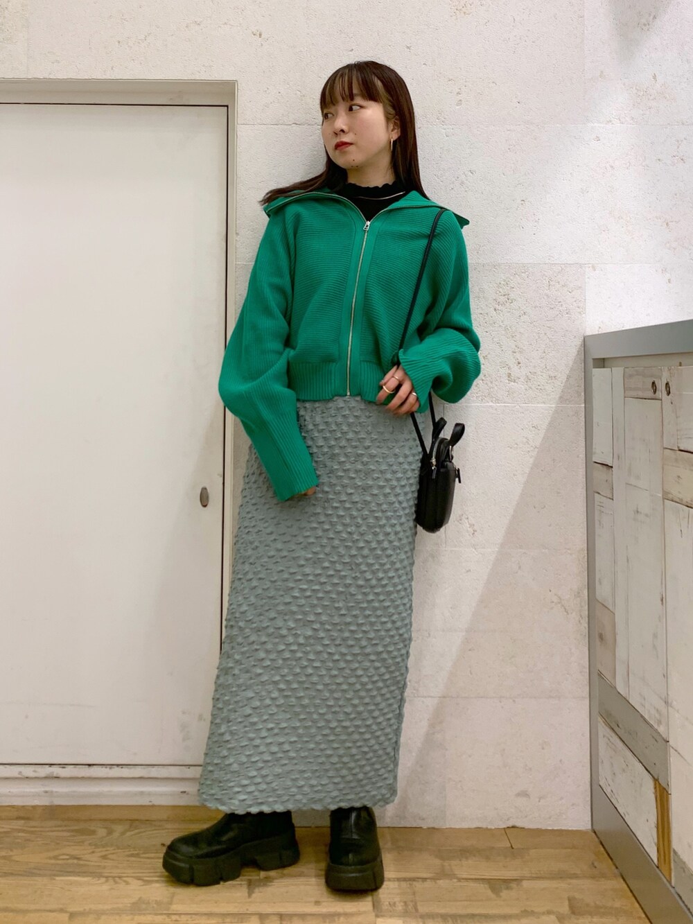 グリーン系のトップス、グリーン系のスカート、ブラック系のショルダーバッグを着用したレディースの冬コーディネートの3枚目の写真