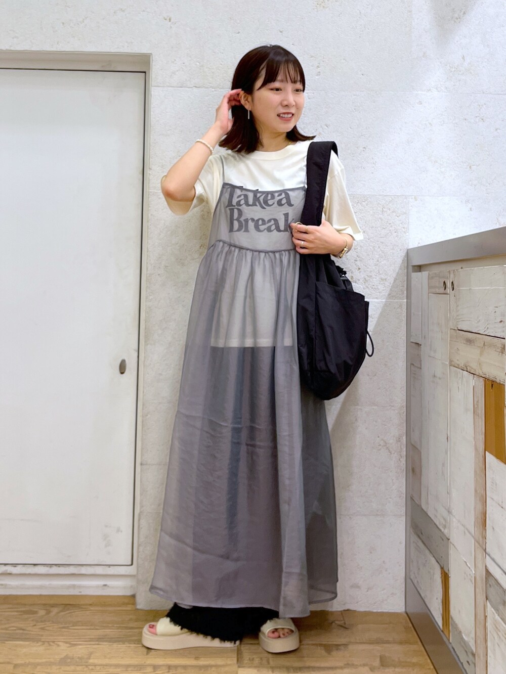 グレー系のワンピース、ホワイト系のシューズ、ブラック系のバッグを着用したレディースの夏コーディネートの3枚目の写真