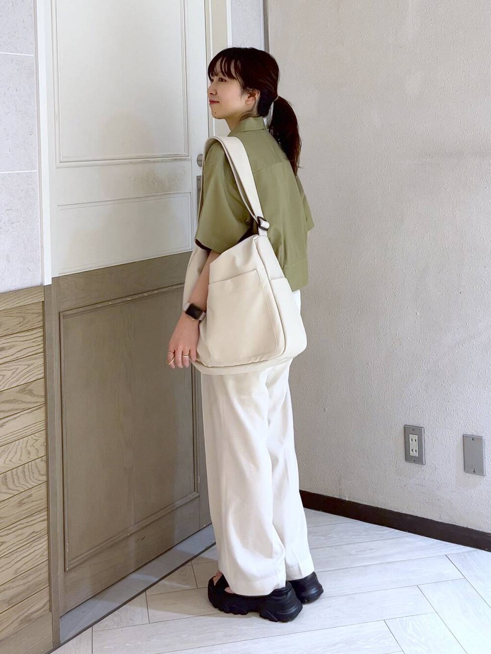 ブラック系のサンダル、ホワイト系のボディバッグ/ウエストポーチ、ホワイト系のスラックスを着用したレディースの春コーディネートの2枚目の写真