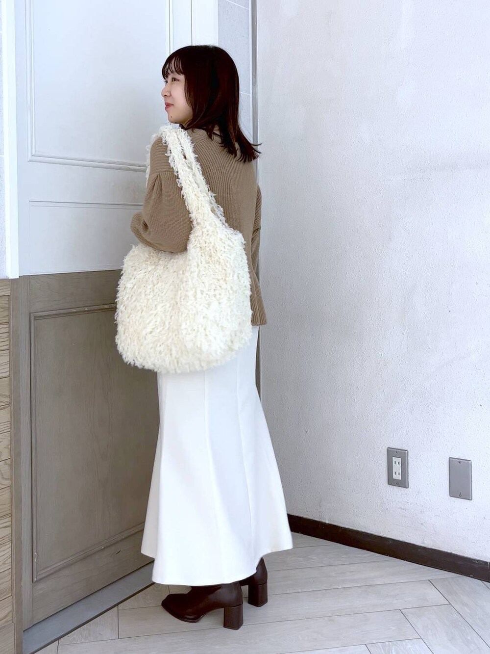 ホワイト系のスカート、ブラウン系のパンプス、ベージュ系のニット/セーターを着用したレディースの冬コーディネートの2枚目の写真