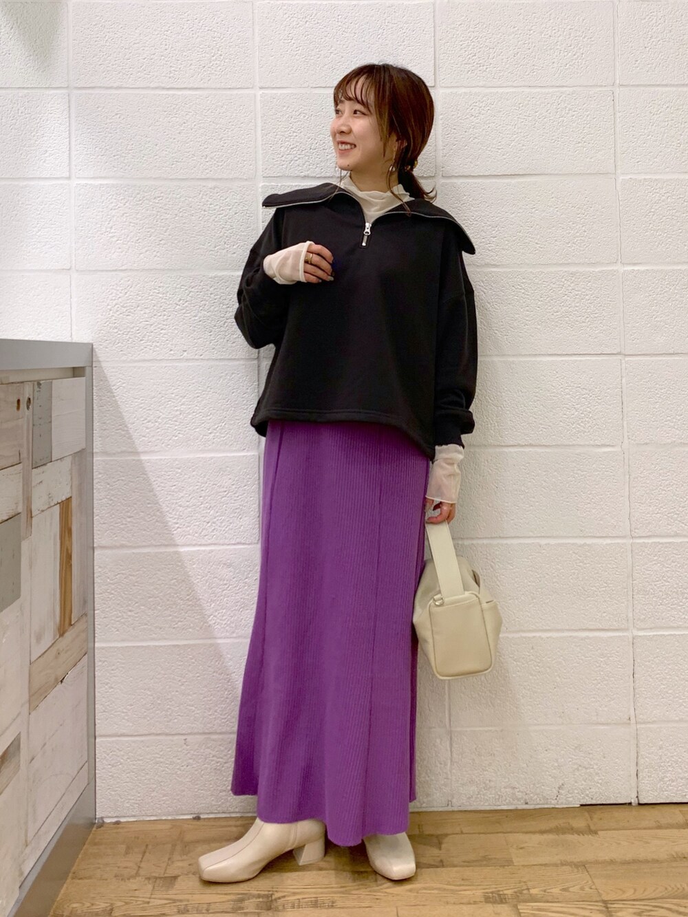 グレー系のトップス、ホワイト系のトップス、パープル系のスカートを着用したレディースの秋コーディネートの3枚目の写真