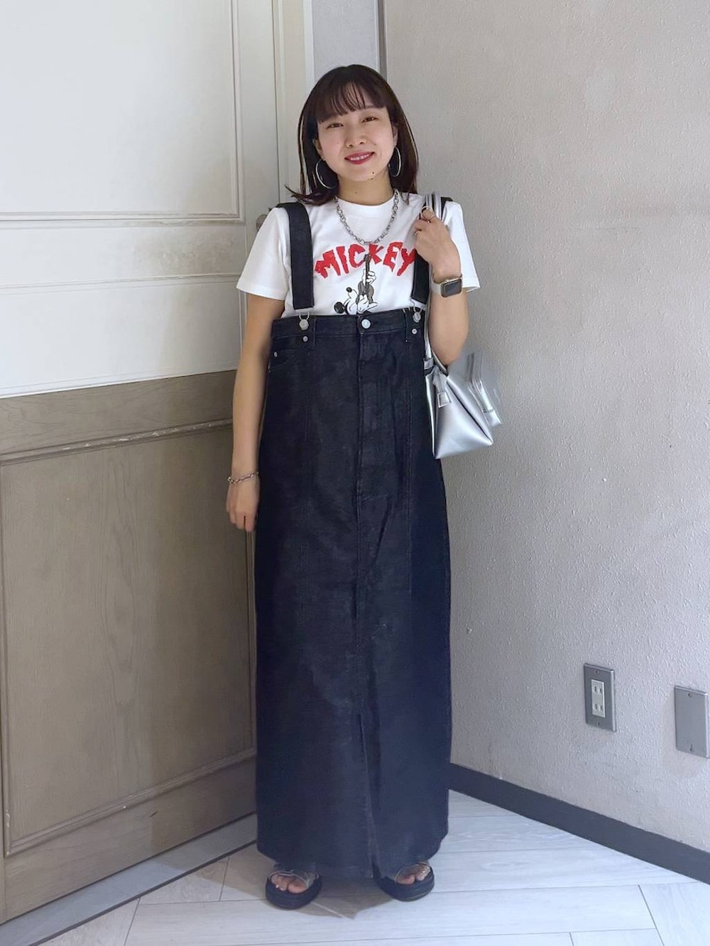 ブラック系のジャンパースカート、シルバー系のスニーカー、シルバー系のショルダーバッグを着用したレディースの夏コーディネートの2枚目の写真