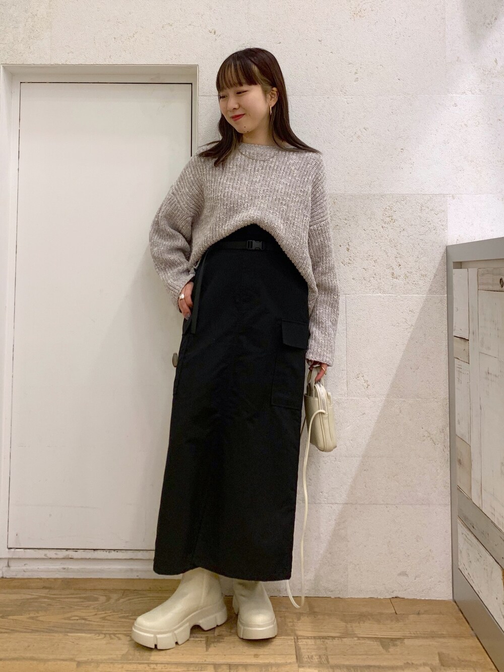 グレー系のニット/セーター、ブラック系のスカート、ブラック系のバッグを着用したレディースの冬コーディネートの2枚目の写真