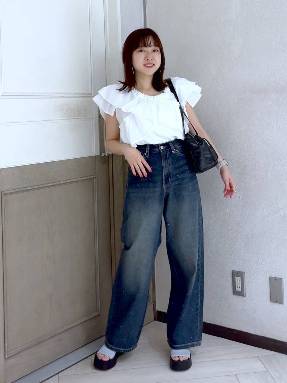 シルバー系のサンダル、ブルー系のデニムパンツ、ブラック系のボストンバッグを着用したレディースの夏コーディネートの2枚目の写真