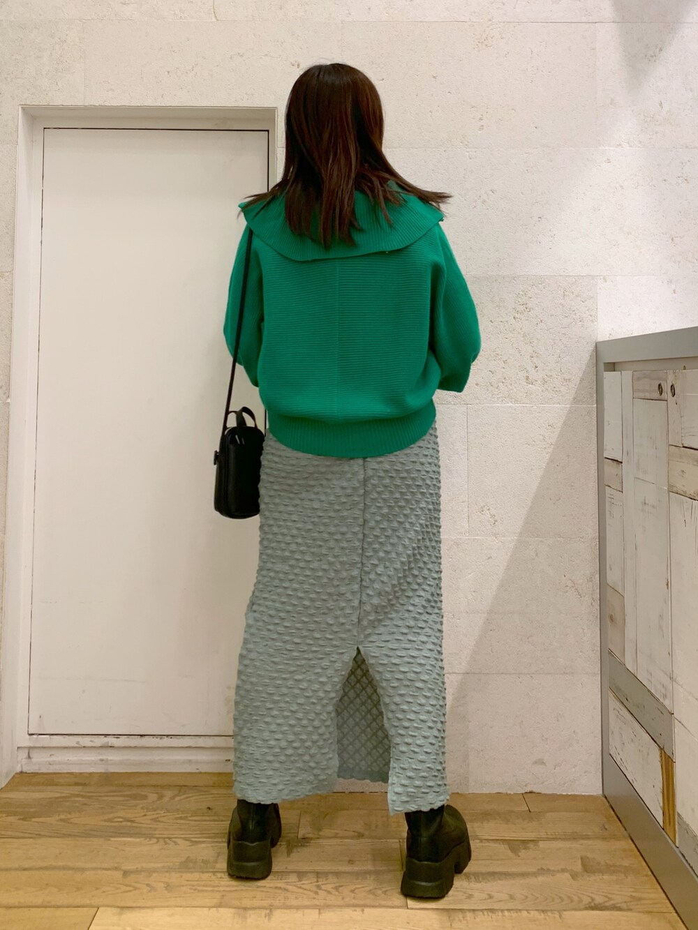 グリーン系のトップス、グリーン系のスカート、ブラック系のショルダーバッグを着用したレディースの冬コーディネートの4枚目の写真