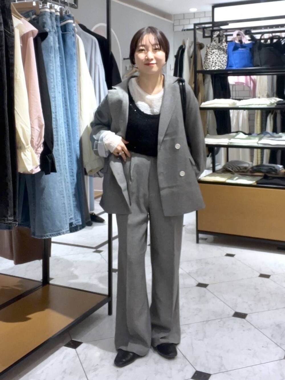 ブラック系のショルダーバッグ、グレー系のスラックス、ブラック系のバレエシューズを着用したレディースの春コーディネートの2枚目の写真