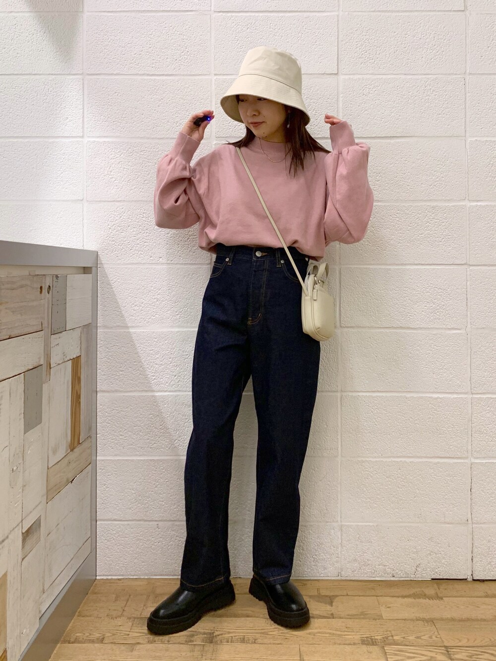 ピンク系のトップス、ブルー系のデニムパンツ、ブラック系のバッグを着用したレディースの秋コーディネートの2枚目の写真