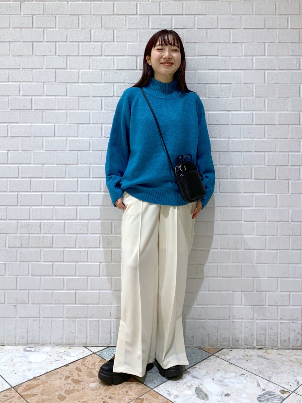 ブルー系のトップス、ブラック系のバッグ、ブラック系のブーツを着用したレディースの冬コーディネートの2枚目の写真