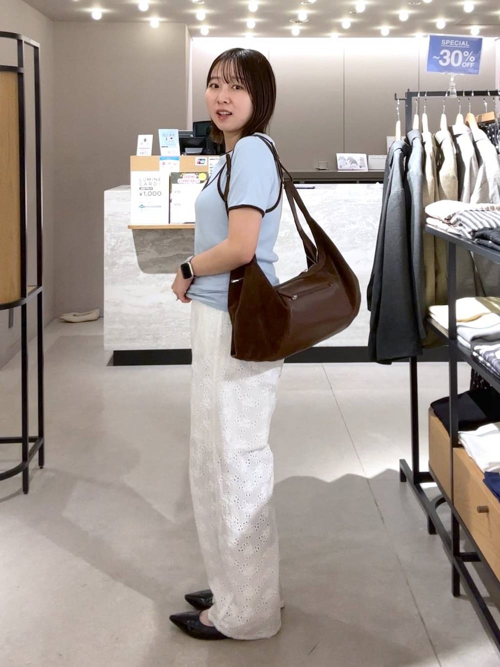 ブラック系のパンプス、ブルー系のTシャツ/カットソー、ブラウン系のショルダーバッグを着用したレディースの春コーディネートの2枚目の写真