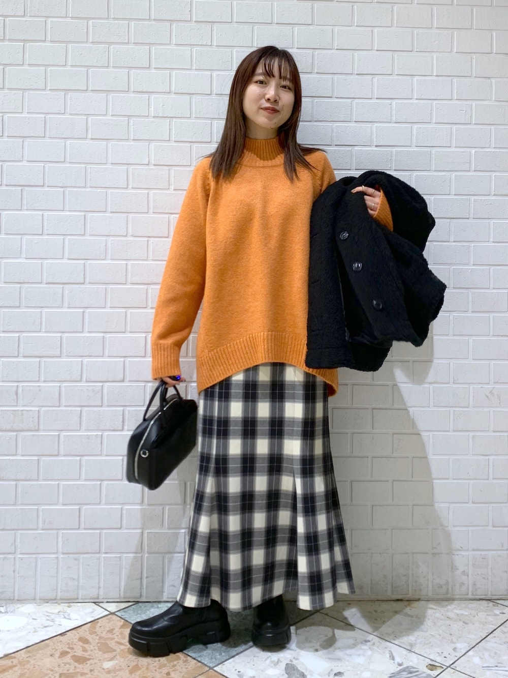 オレンジ系のトップス、ブラック系のスカート、ブラック系のジャケット/アウターを着用したレディースの冬コーディネートの4枚目の写真