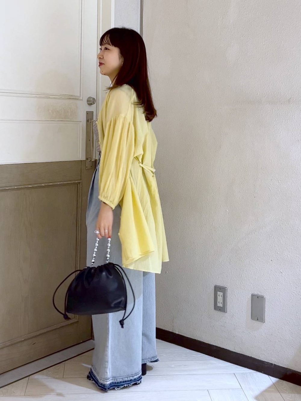 イエロー系のシャツ/ブラウス、ホワイト系のスカート、ホワイト系のサンダルを着用したレディースの夏コーディネートの3枚目の写真