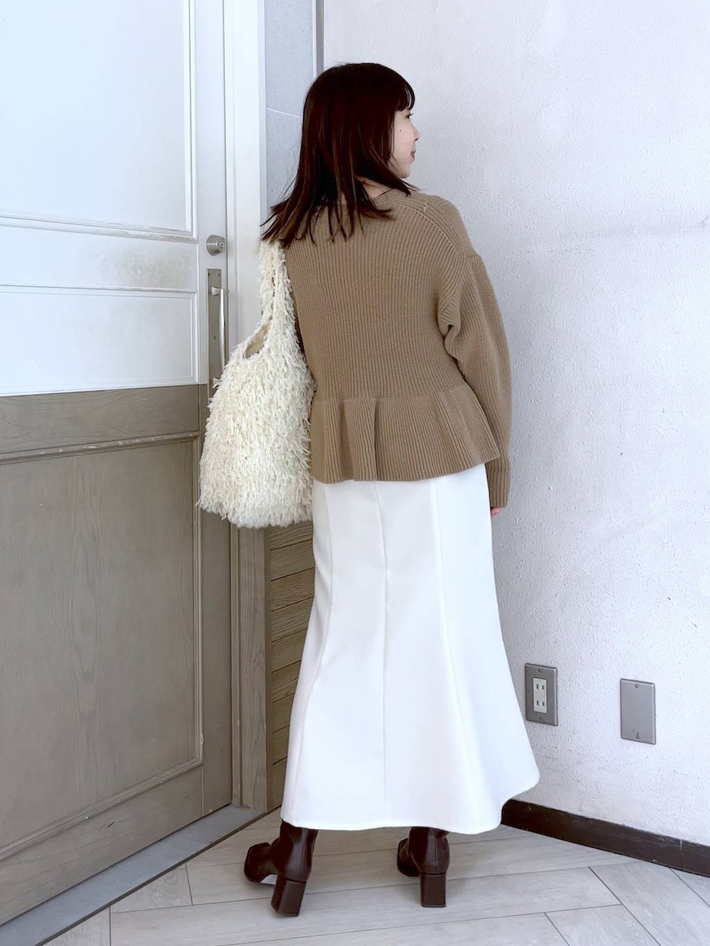 ホワイト系のスカート、ブラウン系のパンプス、ベージュ系のニット/セーターを着用したレディースの冬コーディネートの3枚目の写真