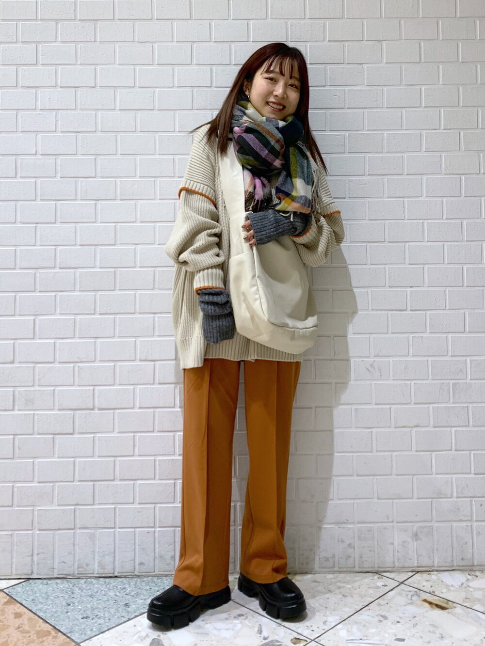 ブラウン系のニット/セーター、オレンジ系のパンツ、ホワイト系のバッグを着用したレディースの冬コーディネートの2枚目の写真