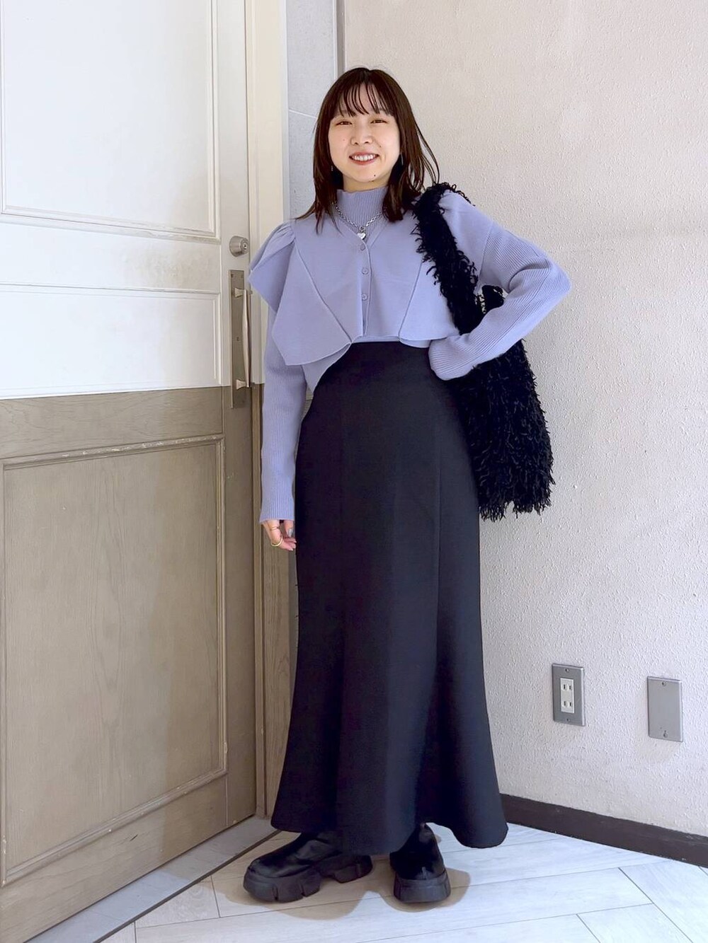 ブラック系のスカート、ブラック系のブーツ、パープル系のニット/セーターを着用したレディースの冬コーディネートの2枚目の写真