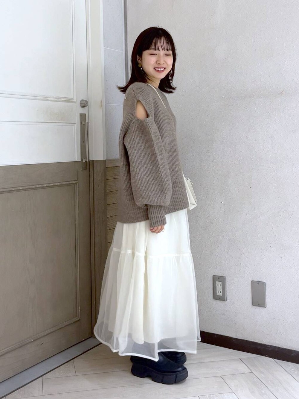 ホワイト系のショルダーバッグ、ブラック系のブーツ、ホワイト系のスカートを着用したレディースの秋コーディネートの4枚目の写真