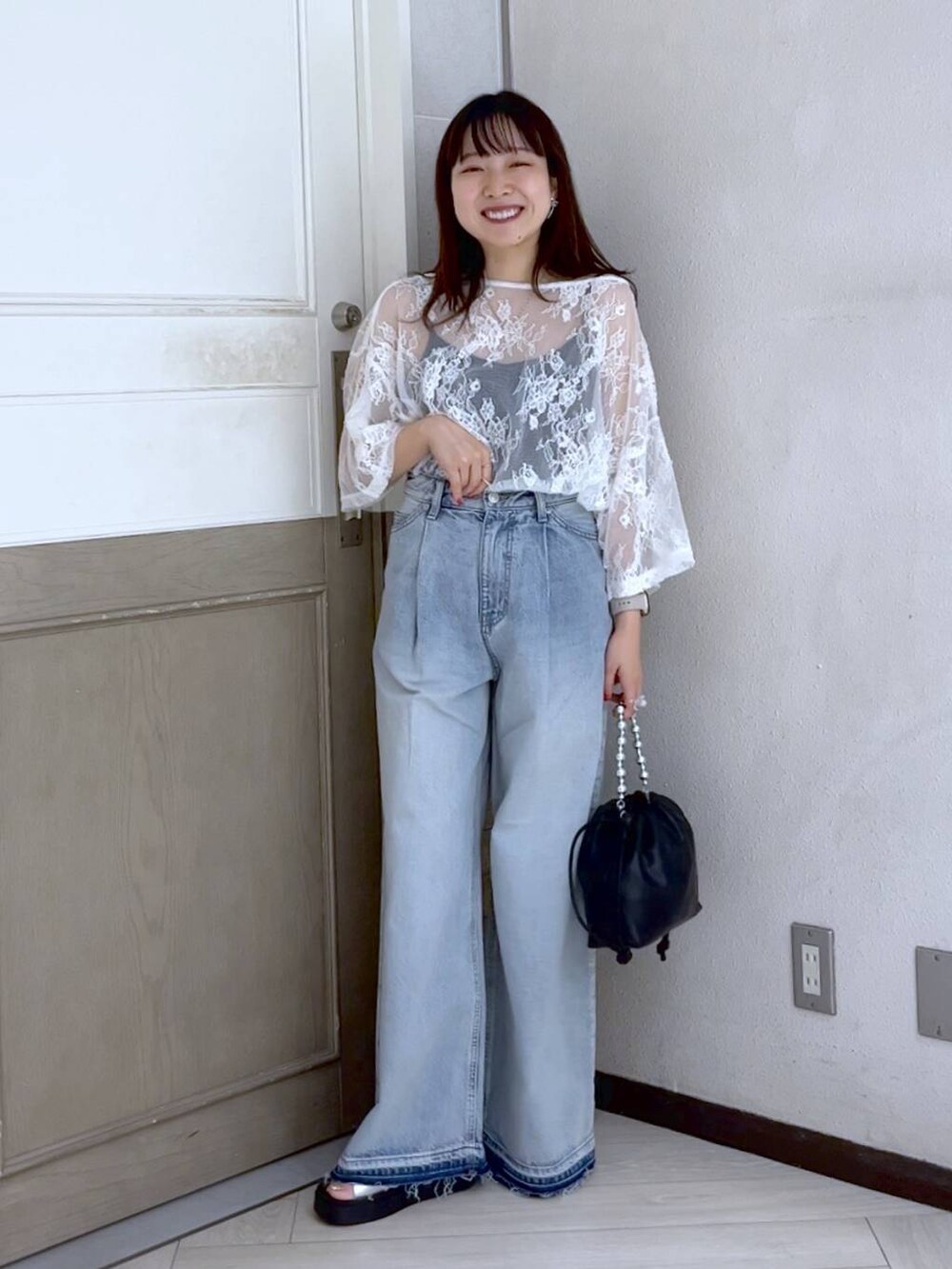 ブルー系のデニムパンツ、シルバー系のサンダル、ブラック系のショルダーバッグを着用したレディースの夏コーディネートの2枚目の写真