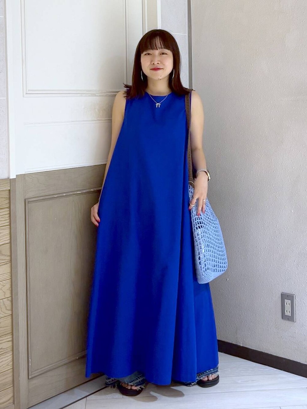 ブルー系のショルダーバッグ、ブルー系のワンピース、シルバー系のスニーカーを着用したレディースの夏コーディネートの2枚目の写真