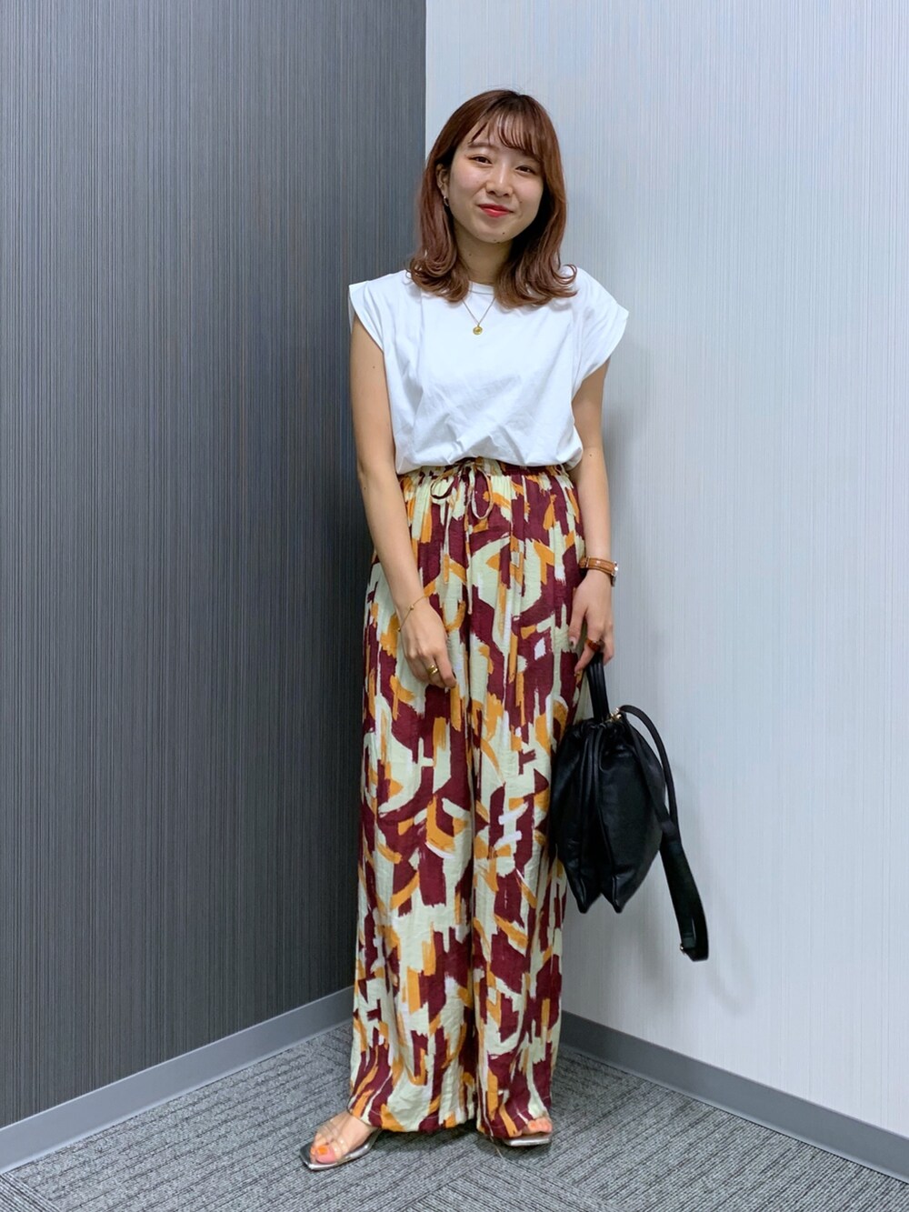 ホワイト系のTシャツ/カットソー、レッド系のパンツ、ブラック系のショルダーバッグを着用したレディースの秋コーディネートの2枚目の写真