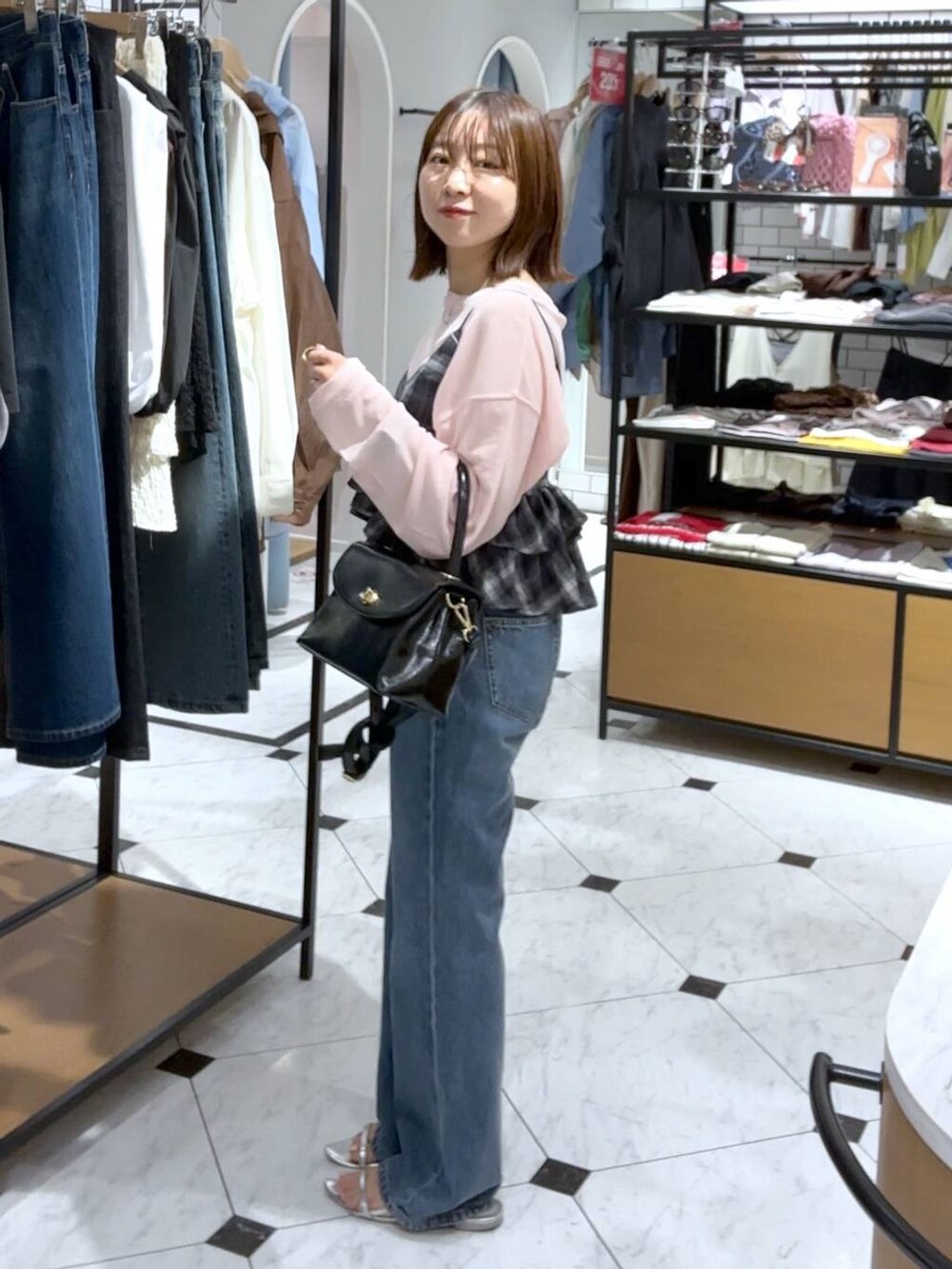 シルバー系のサンダル、ブルー系のデニムパンツ、ブラック系のボストンバッグを着用したレディースの夏コーディネートの2枚目の写真