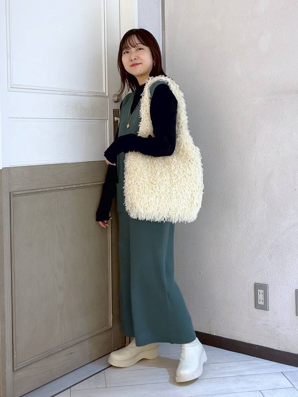 ホワイト系のブーツ、グリーン系のワンピース、ホワイト系のトートバッグを着用したレディースの冬コーディネートの4枚目の写真