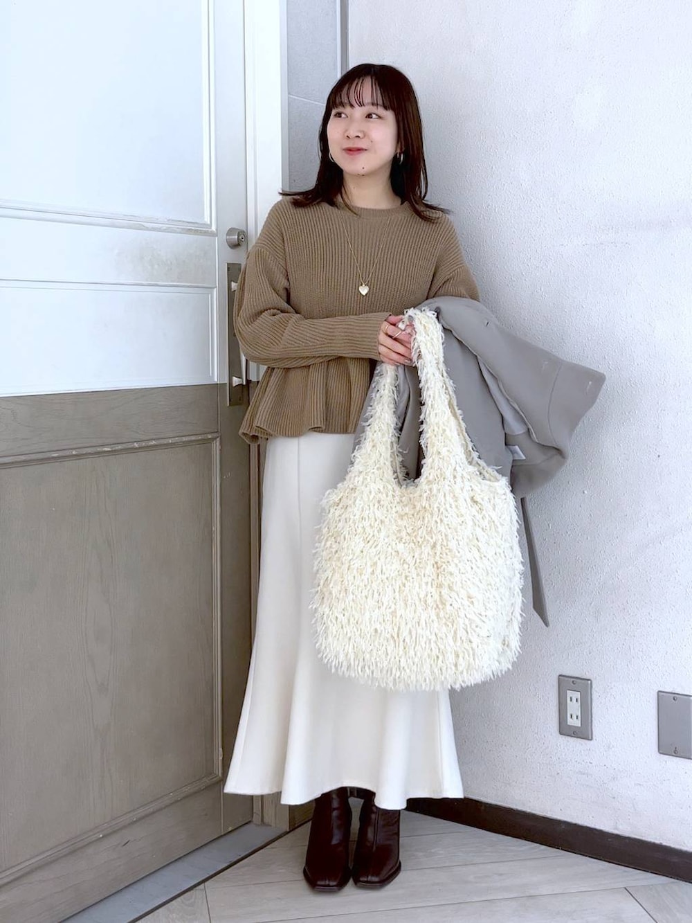 ホワイト系のスカート、ホワイト系のその他アウター、ブラウン系のパンプスを着用したレディースの冬コーディネートの4枚目の写真