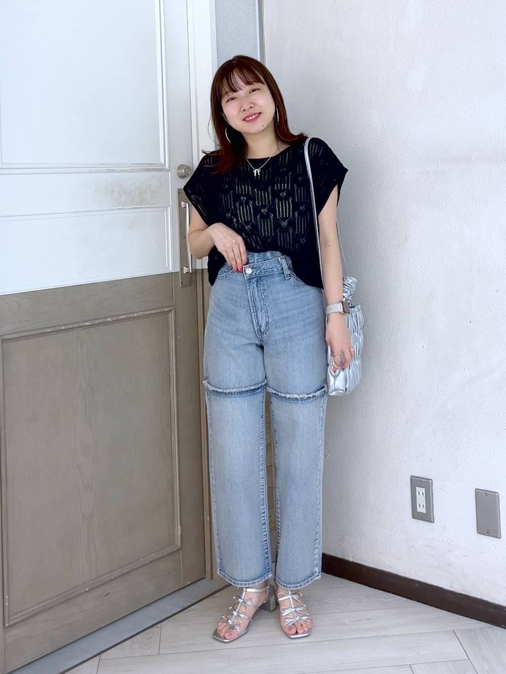 シルバー系のサンダル、ブルー系のデニムパンツ、ブラック系のニット/セーターを着用したレディースの夏コーディネートの2枚目の写真