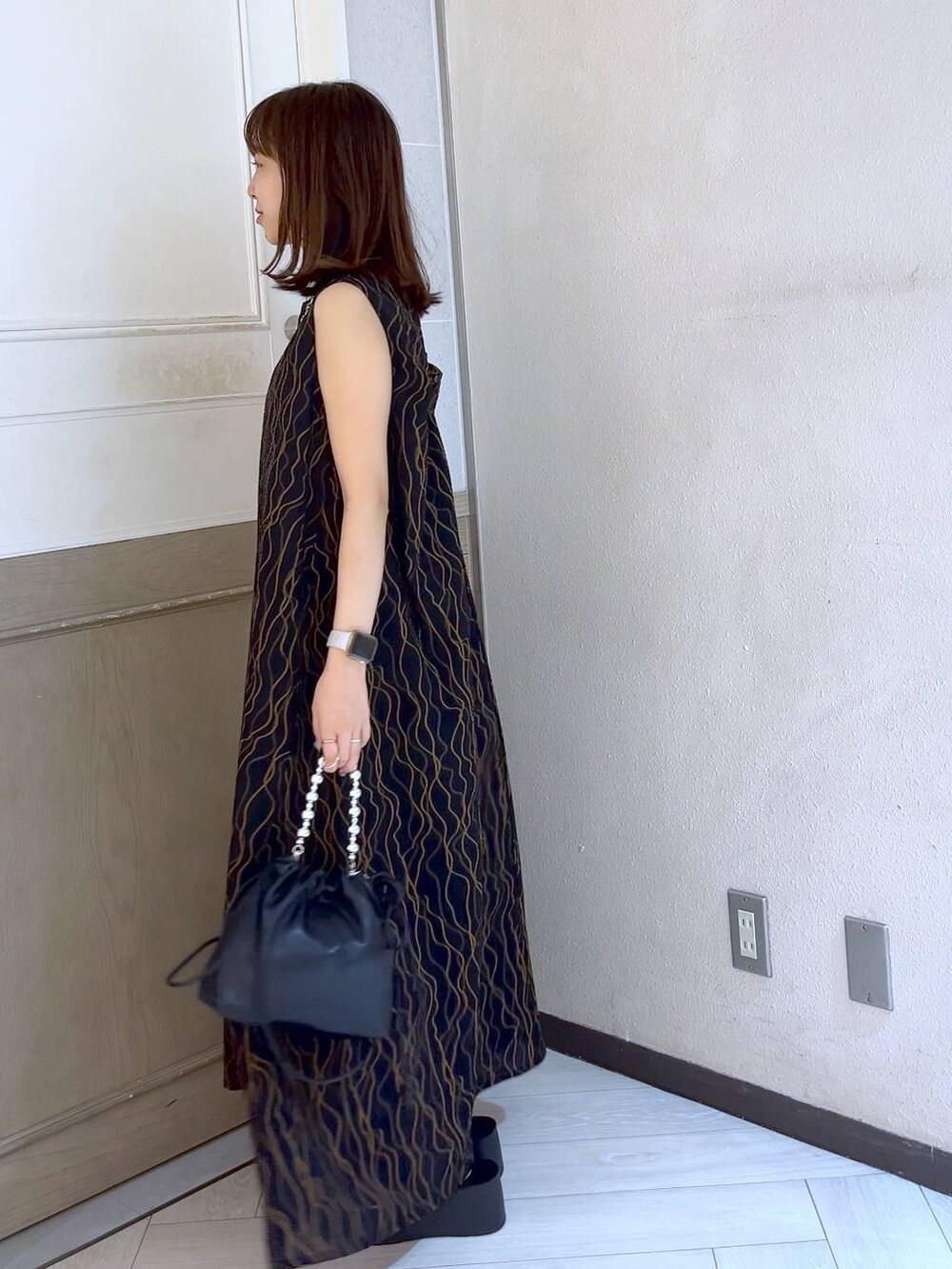 ブラック系のショルダーバッグ、ブラック系のサンダル、ブラック系のワンピースを着用したレディースの夏コーディネートの2枚目の写真