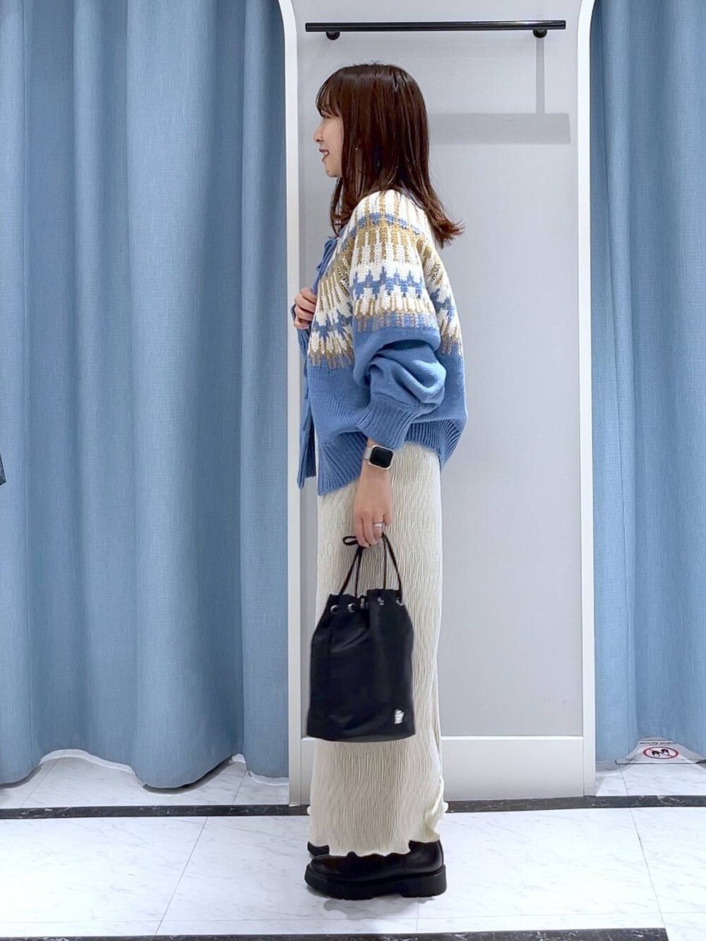 ブラック系のブーツ、ホワイト系のスカート、ブラック系のハンドバッグを着用したレディースの冬コーディネートの3枚目の写真