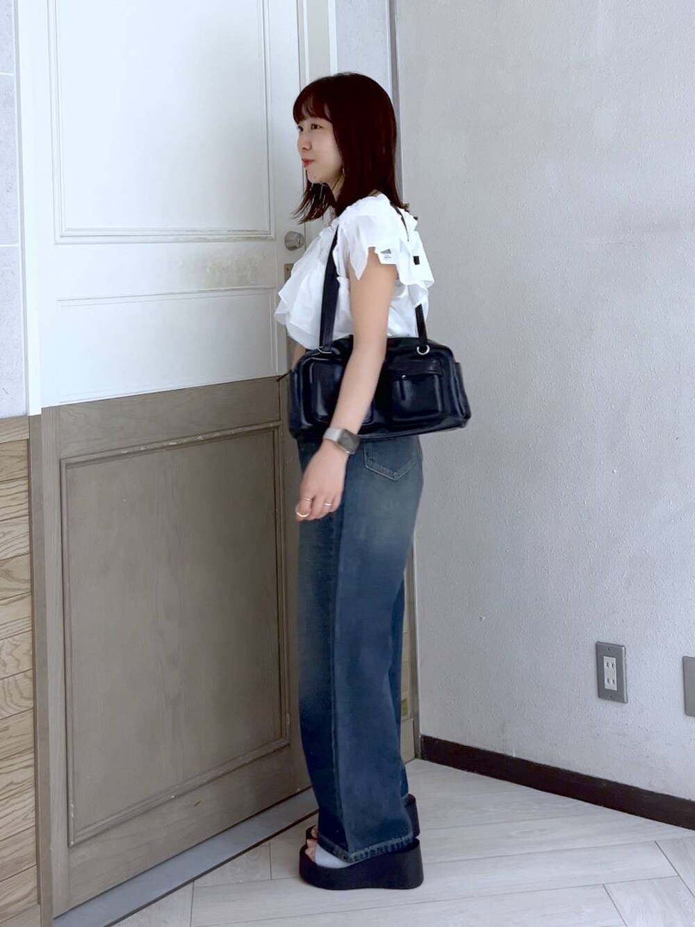 シルバー系のサンダル、ブルー系のデニムパンツ、ブラック系のボストンバッグを着用したレディースの夏コーディネートの3枚目の写真